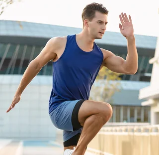 Male model running in a navy scoop-neck singlet; shorts shown are separate