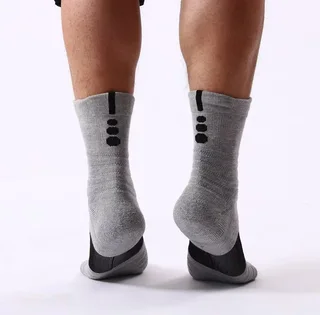 Gray crew sports socks worn on feet, showing the heel construction and contrasting black knit details