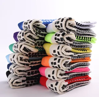 Stacked football grip socks in multiple colors with folded soles showing the rectangular pad pattern